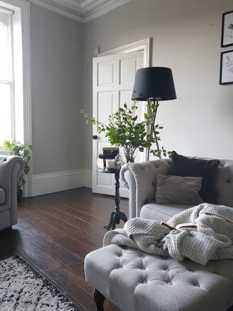 Soft grey Victorian living room with grey Chesterfield sofa and footstool. Black lamp and side table. From a blog post about neutral paint colours by Life with Holly, a period interiors blog. 