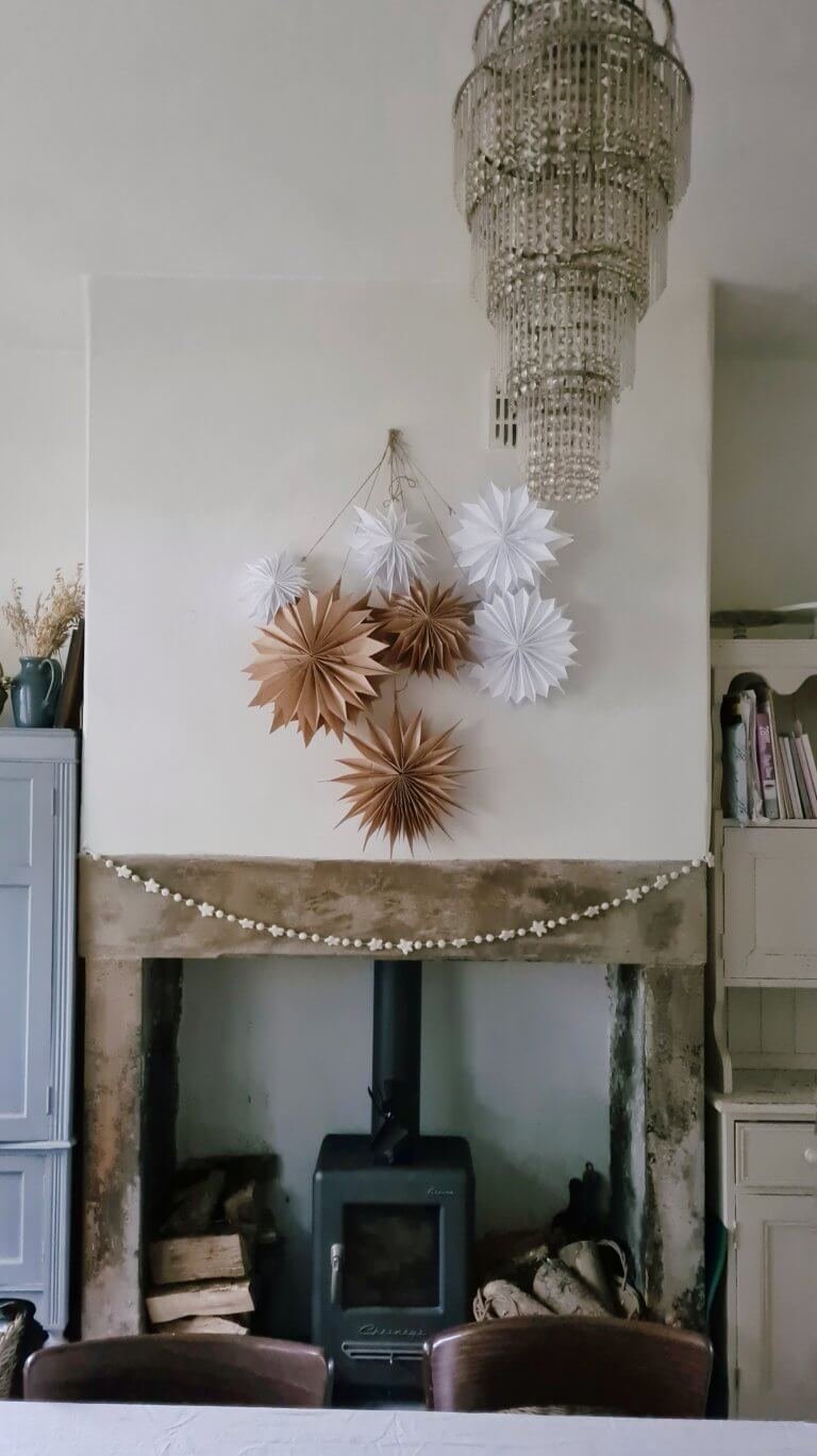 Brown paper bag stars and white paper bag stars above a fireplace from a blog post about how to make easy paper bag stars by Life with Holly