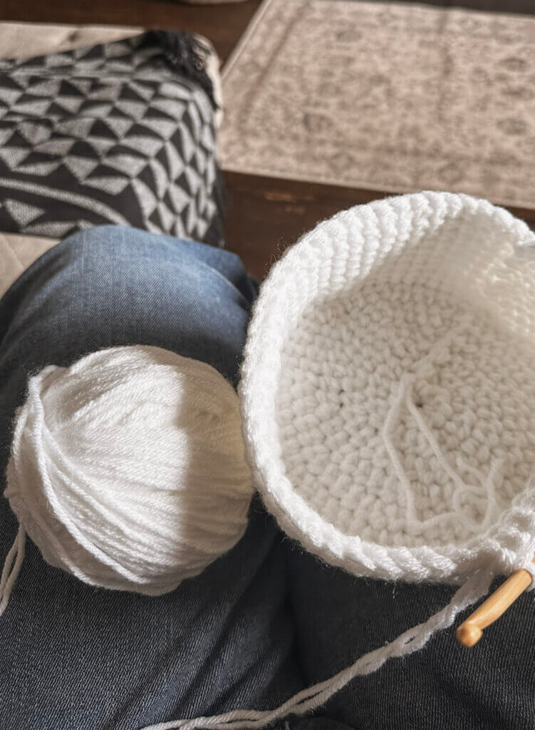 A partially completed white crochet basket
